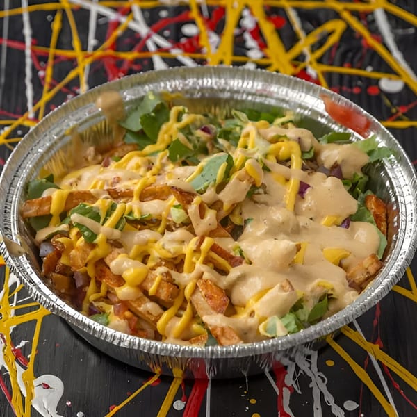 Halal Hen's loaded fries with cheese sauce, white sauce, and fresh greens in a foil container.