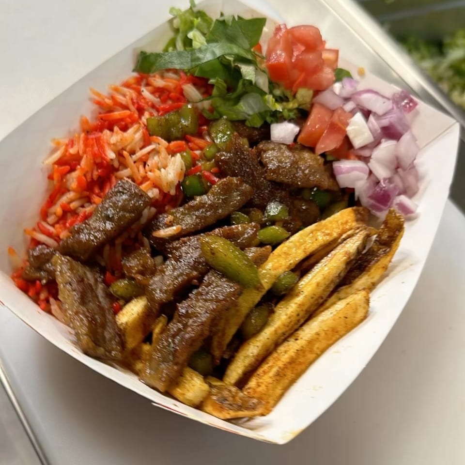 Halal Hen's platter with red rice, beef, fries, lettuce, tomatoes, and red onions.