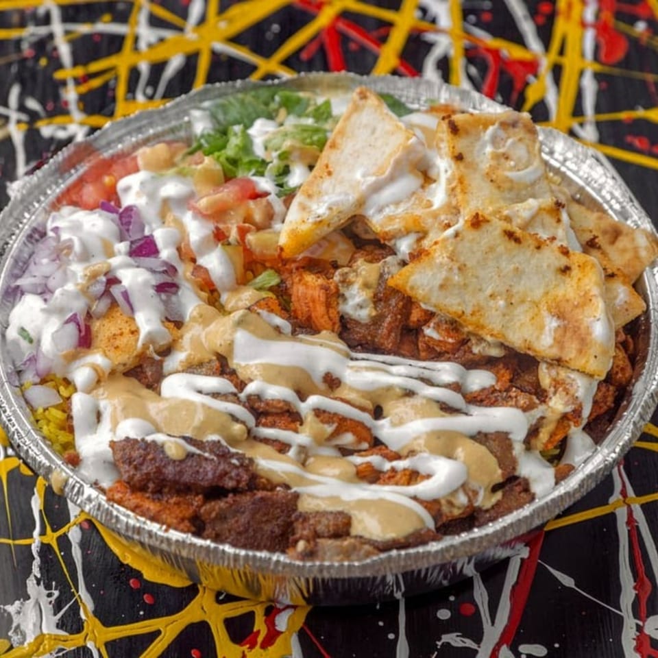 A Halal Hen platter with chicken, lamb, rice, salad, pita, white sauce, and hot sauce.
